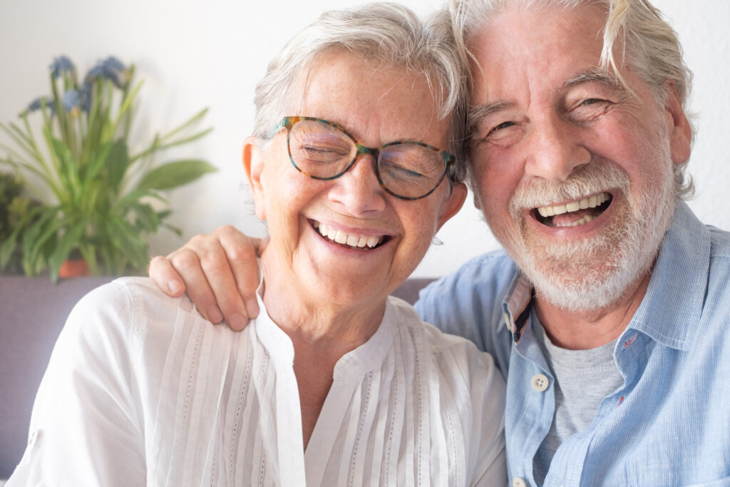 Beautiful senior couple  having fun and laughing sitting at home on sofa. Serene elderly people enjoying retirement