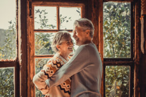 Happiness and togetherness concept lifestyle with senior retired caucasian couple enjoy love and relationship at home hugging and laughing. Man and woman elderly life concept indoor