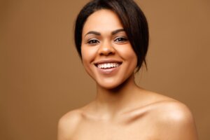 Beauty Portrait of attractive African American young woman with perfect skin and natural make up. Beautiful brunette model. Skin Face Care Concept. Looking on camera against brown background