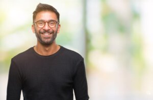 Adult hispanic man wearing glasses over isolated background with a happy and cool smile on face. Lucky person.