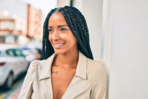 Young african american woman smiling happy leaning on the wall at the city.